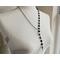 Asymmetrical lariat necklace: one side black coin beads, silver spacers, pewter dangle, other side rhodium chain connected by pewter loop