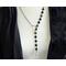 Asymmetrical lariat necklace: one side black coin beads, silver spacers, pewter dangle, other side rhodium chain connected by pewter loop