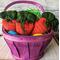 Medium dark orange crochet carrot pouches in an Easter basket. Pouches are around 5 inches wide at the top and 6 inches long. Tied in front.