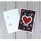 A valentine card making kit of 12 with black scrapbook paper with hearts, white and red heart embellishments, and white cards and envelopes.