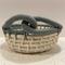 A small round woven cream basket with a laurel green decorative knot design on the rim.