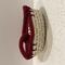 A small round woven cream basket with a wine colored decorative knot design on the rim.