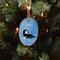 A wood slice ornament with a hand-painted hooded merganser on water offered at Cove Creek Photography.