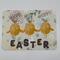 Yellow chicks wearing bunny ears and shiny pink cheeks accented with paint with Easter spelled out in chocolate 
