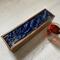 Deep navy is the background for this ocean inspired tea box.  Waves of white are accented by metallic gold in the resin.  This mango wood tea organizer can hold up to 50 tea bags for entertaining.