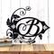 Metal monogram plaque with vines surrounding the letter, B, in matte black powder coat.