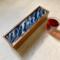 Bold ocean wave pattern on top of this wooden tea caddy that holds 50 tea bags.