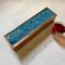 Warm, rich shades of blue interspersed with ribbons of metallic gold form a design on top of this tea organizing box that holds up to 50 tea bags.  This tea box is handmade of mango wood with a hinged top and has 5 compartments for organizing your tea bags.  Perfect gift for tea lover or someone who loves to entertain.  Adds a pop of color and luxury to any home decor.