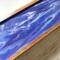 A close up of the design created with quality acrylics and glossy resin.  Shades of purple swirl together with white on the cover of this 5-compartment tea chest.