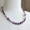 18 in long necklace - amethyst coin and charoite beads, glass tulip beads, and platinum plated cubic zirconia butterfly.