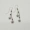 Handmade 2.5 inch dangle earrings with violet swirl crystal beads and silver daisy flower charms on delicate chains.