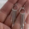  Close-up of a hand holding a pair of 925 sterling silver fringe dangle earrings with multiple dangling elements.  
