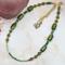 An 18-inch handmade necklace with vintage olive-green glass beads, bicones, and seed beads on a gold-plated stainless steel chain