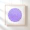On a bright white wall, the amulet is in a blond wood frame. 