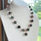 Moss agate beads in shades of teal, green and blue are linked by wire wrapping to form a necklace with copper clasp. 