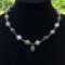 Moss agate beads in shades of teal, green and blue are linked by wire wrapping to form a necklace with copper clasp. 