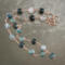 Moss agate beads in shades of teal, green and blue are linked by wire wrapping to form a necklace with copper clasp. 