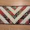 Small table runner with elegant red, green, and black fabric in a chevron pattern.