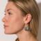  Side view of a person wearing a sterling silver hammered pear dangle earring, showcasing the design and ear wire.

