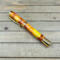 Red yellow and orange swirled resin rollerball pen with gold components 