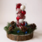 Handmade Christmas centerpiece with red and white swirl ornaments in glass vase, pine greenery, pinecones and blue light on wood slice base
