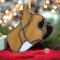 French Bulldog Stained Glass ornament made of tan colored glass, sitting on a red cushion with small gifts around and Christmas lights in the background.