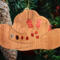 Handmade wooden Christmas tree ornament shaped like a cowboy hat, featuring a sprig of holly tucked into the hat band, star-shaped leaf cutouts, and round berry accents.