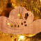 Handmade wooden Christmas tree ornament shaped like a cowboy hat, featuring a sprig of holly tucked into the hat band, star-shaped leaf cutouts, and round berry accents.