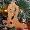 Handmade wooden Christmas tree ornament shaped like a cowboy boot, featuring a sprig of holly On the side of the boot, and round berry accents.