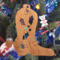 Handmade wooden Christmas tree ornament shaped like a cowboy boot, featuring a sprig of holly On the side of the boot, and round berry accents.