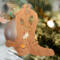 Handmade wooden Christmas tree ornament shaped like a cowboy boot, featuring a sprig of holly On the side of the boot, and round berry accents.
