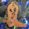 Handmade wooden Christmas tree ornament shaped like a cowboy boot, featuring a sprig of holly On the side of the boot, and round berry accents.
