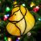 Pomeranian stained glass ornament in light red/orange-  shown hanging on a Christmas tree.