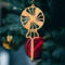 A handcrafted wooden Christmas tree ornament shaped like a lollipop, featuring intricate cut-out spiral patterns on the circular top and a simple stick base. The ornament is light brown with a smooth finish.