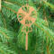 A handcrafted wooden Christmas tree ornament shaped like a lollipop, featuring intricate cut-out spiral patterns on the circular top and a simple stick base. The ornament is light brown with a smooth finish.