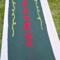 A dark green and red table runner with God Bless Us Every One in the center, poinsettias on either end. And yellow swirls around the quote.