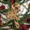Handmade wooden Christmas tree ornament shaped like a curved candy cane with intricate stripe cutouts, accented by a delicate bow and crafted from natural light colored wood tones.