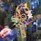Handmade wooden Christmas tree ornament shaped like a curved candy cane with intricate stripe cutouts, accented by a delicate bow and crafted from natural light colored wood tones.