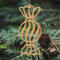 A handmade wooden Christmas tree ornament shaped like a wrapped hard candy, featuring a bulbous center with swirling stripes and twisted wrapper ends, crafted from light-toned wood using a scroll saw.