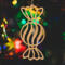 A handmade wooden Christmas tree ornament shaped like a wrapped hard candy, featuring a bulbous center with swirling stripes and twisted wrapper ends, crafted from light-toned wood using a scroll saw.