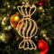 A handmade wooden Christmas tree ornament shaped like a wrapped hard candy, featuring a bulbous center with swirling stripes and twisted wrapper ends, crafted from light-toned wood using a scroll saw.