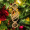 A handcrafted wooden Christmas tree ornament shaped like a wrapped candy, featuring intricate Victorian fretwork with twisted ends and a diagonal swirling stripe in the center.