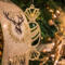 A handcrafted wooden Christmas tree ornament shaped like a wrapped candy, featuring intricate Victorian fretwork with twisted ends and a diagonal swirling stripe in the center.