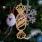 A handcrafted wooden Christmas tree ornament shaped like a wrapped candy, featuring intricate Victorian fretwork with twisted ends and a diagonal swirling stripe in the center.