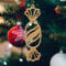 A handcrafted wooden Christmas tree ornament shaped like a wrapped candy, featuring intricate Victorian fretwork with twisted ends and a diagonal swirling stripe in the center.