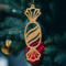 A handcrafted wooden Christmas tree ornament shaped like a wrapped candy, featuring intricate Victorian fretwork with twisted ends and a diagonal swirling stripe in the center.