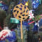 A handmade Christmas tree ornament crafted from light brown maple hardwood plywood, shaped like a lollipop with a round head featuring intricate spiral cutouts and a long stick handle, suspended from a small metal hook.