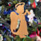 A handmade wooden Christmas ornament in the shape of a cheerful angel, featuring a halo, wings, and a raised arm ringing a bell, hand-cut from solid hardwood and finished with clear shellac.