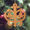Intricate Victorian-style fretwork Christmas tree ornament handcrafted from natural hardwood with visible wood grain, showcasing symmetrical curls, loops, and ornate cut-out designs.
