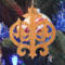 Intricate Victorian-style fretwork Christmas tree ornament handcrafted from natural hardwood with visible wood grain, showcasing symmetrical curls, loops, and ornate cut-out designs.